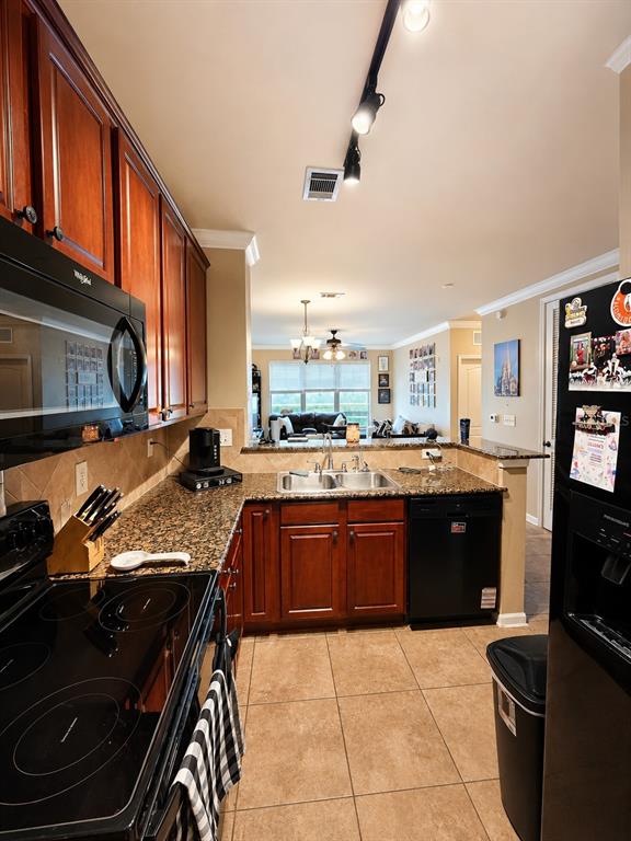 A kitchen features dark wood cabinets, granite countertops, and black appliances, opening to a living area — 901 CHARO PARKWAY UNIT 714, DAVENPORT, FL