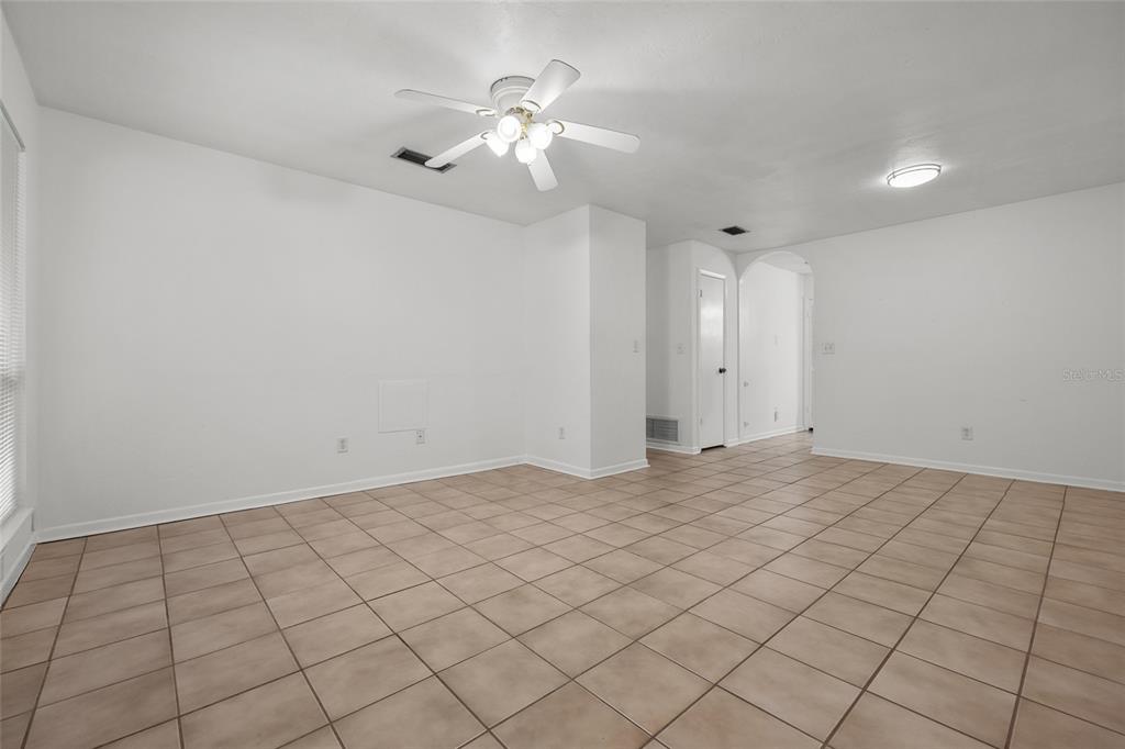 A bright, empty room features white walls, tan tile flooring, and a ceiling fan — 4219 NW 30TH TERRACE, GAINESVILLE, FL