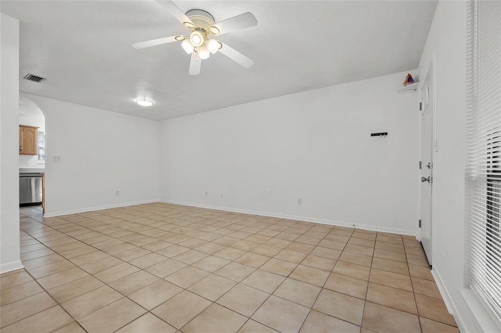 A bright, empty room features white walls, tan tile flooring, and a ceiling fan — 4219 NW 30TH TERRACE, GAINESVILLE, FL