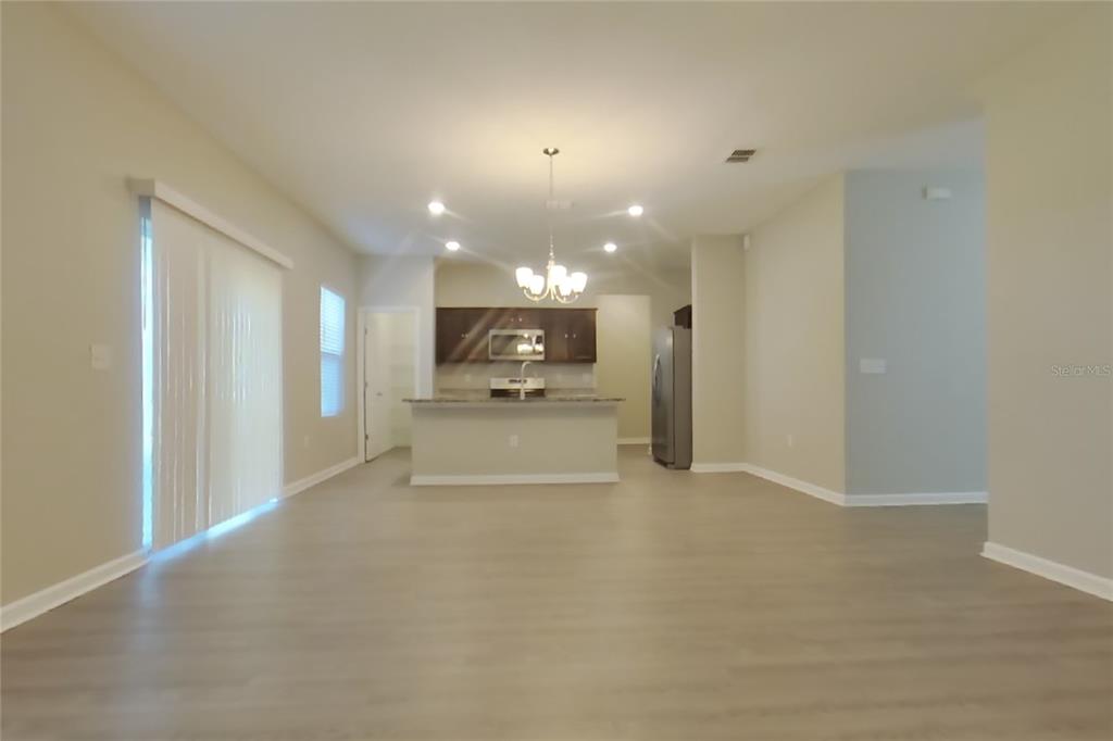 An open-concept kitchen with a breakfast bar overlooks a spacious living area with light flooring — 15619 MERLIN AVENUE, MASCOTTE, FL