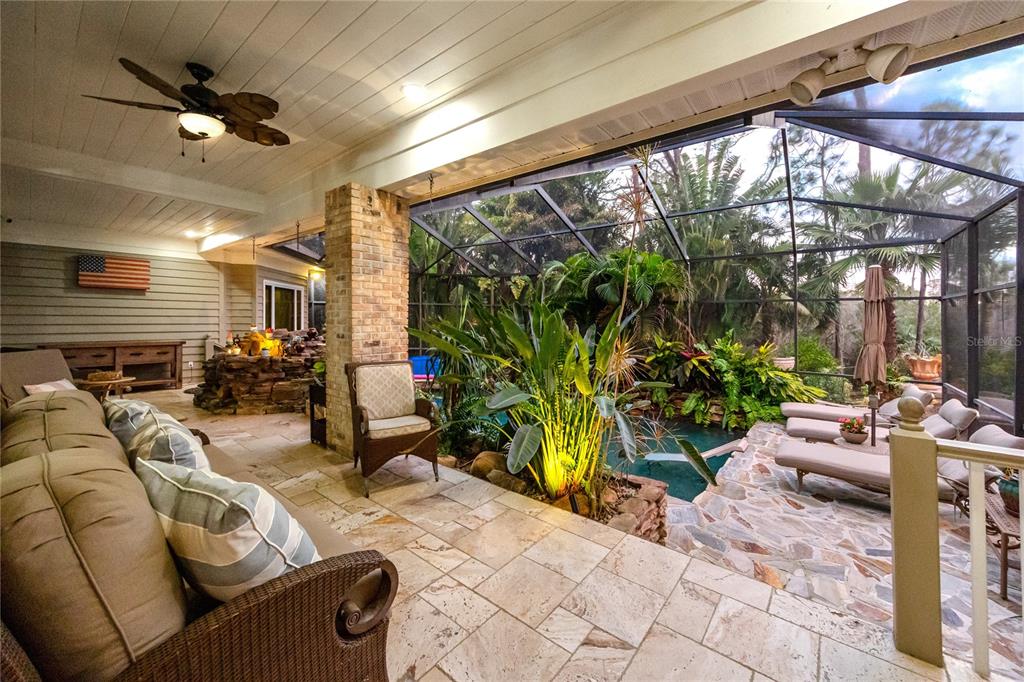 A covered patio features stone flooring, a ceiling fan, and a screened-in pool area — 2780 LONG PUTT COURT, PALM HARBOR, FL