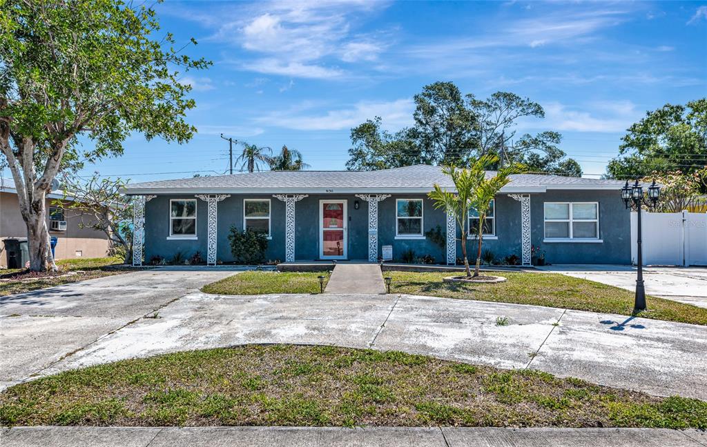 A single-story gray house with a concrete driveway and a front walkway under a blue sky — 6511 GEORGIA AVENUE, BRADENTON, FL