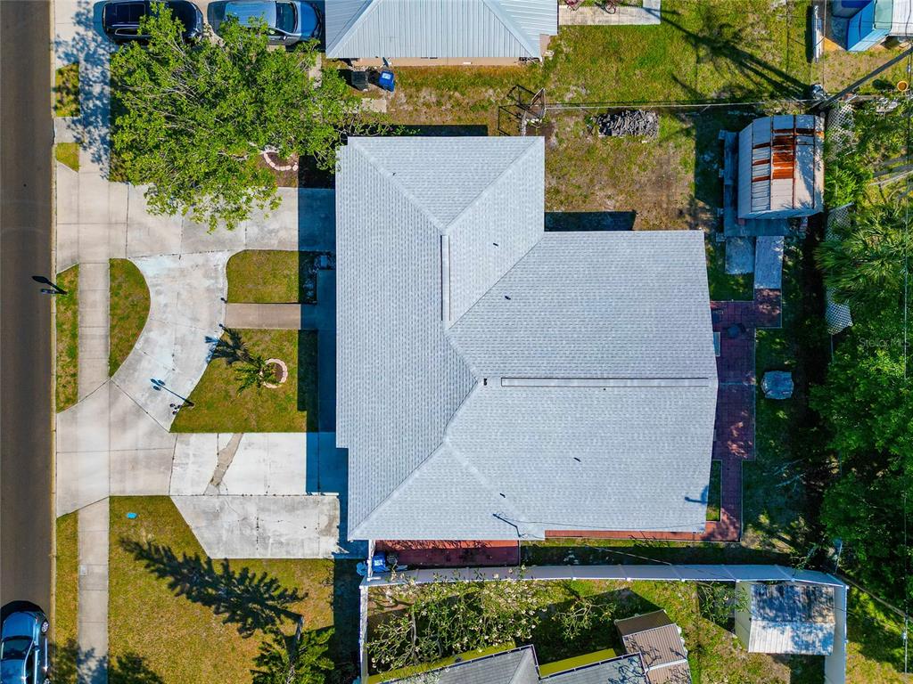 An aerial view shows a house with a gray shingled roof, driveway, and backyard — 6511 GEORGIA AVENUE, BRADENTON, FL