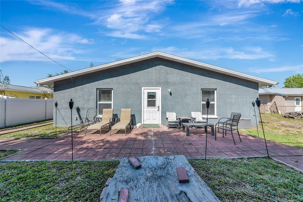 The back exterior of a gray house features a paved patio with outdoor furniture — 6511 GEORGIA AVENUE, BRADENTON, FL