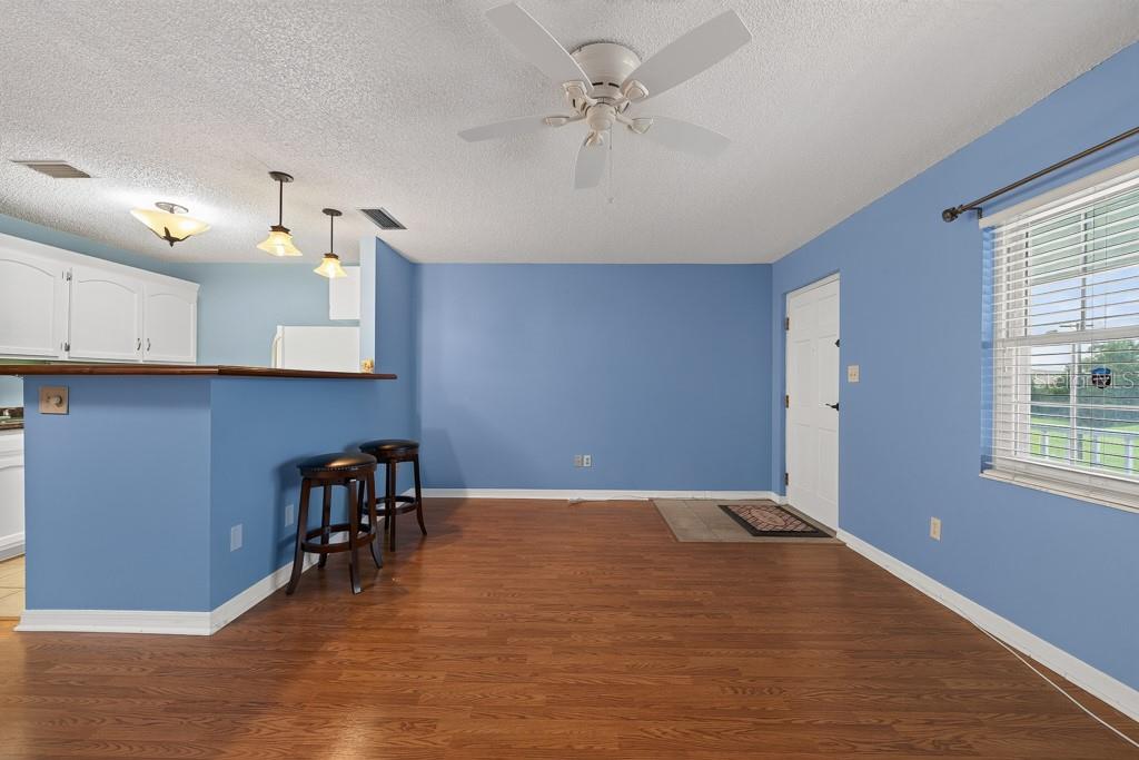 A dining area with blue walls, wood flooring, a ceiling fan, and a breakfast bar — 4801 AIRPORT ROAD UNIT 118, ZEPHYRHILLS, FL
