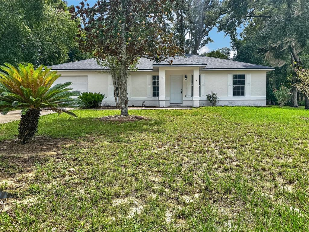 A single-story white house with a gray roof, a front porch, and a grassy yard — 19 JUNIPER PASS TRACK, OCALA, FL