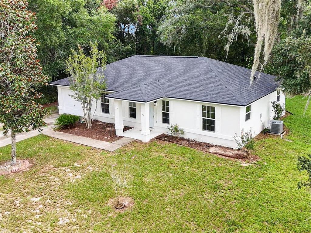 An aerial view of a white, single-story house with a dark shingled roof and landscaping — 19 JUNIPER PASS TRACK, OCALA, FL
