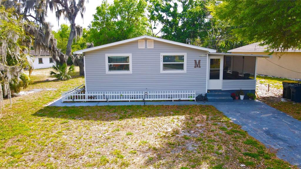 A light gray, single-story house with a white picket fence and a screened-in porch — 111 NE PALENCIA ROAD, AUBURNDALE, FL