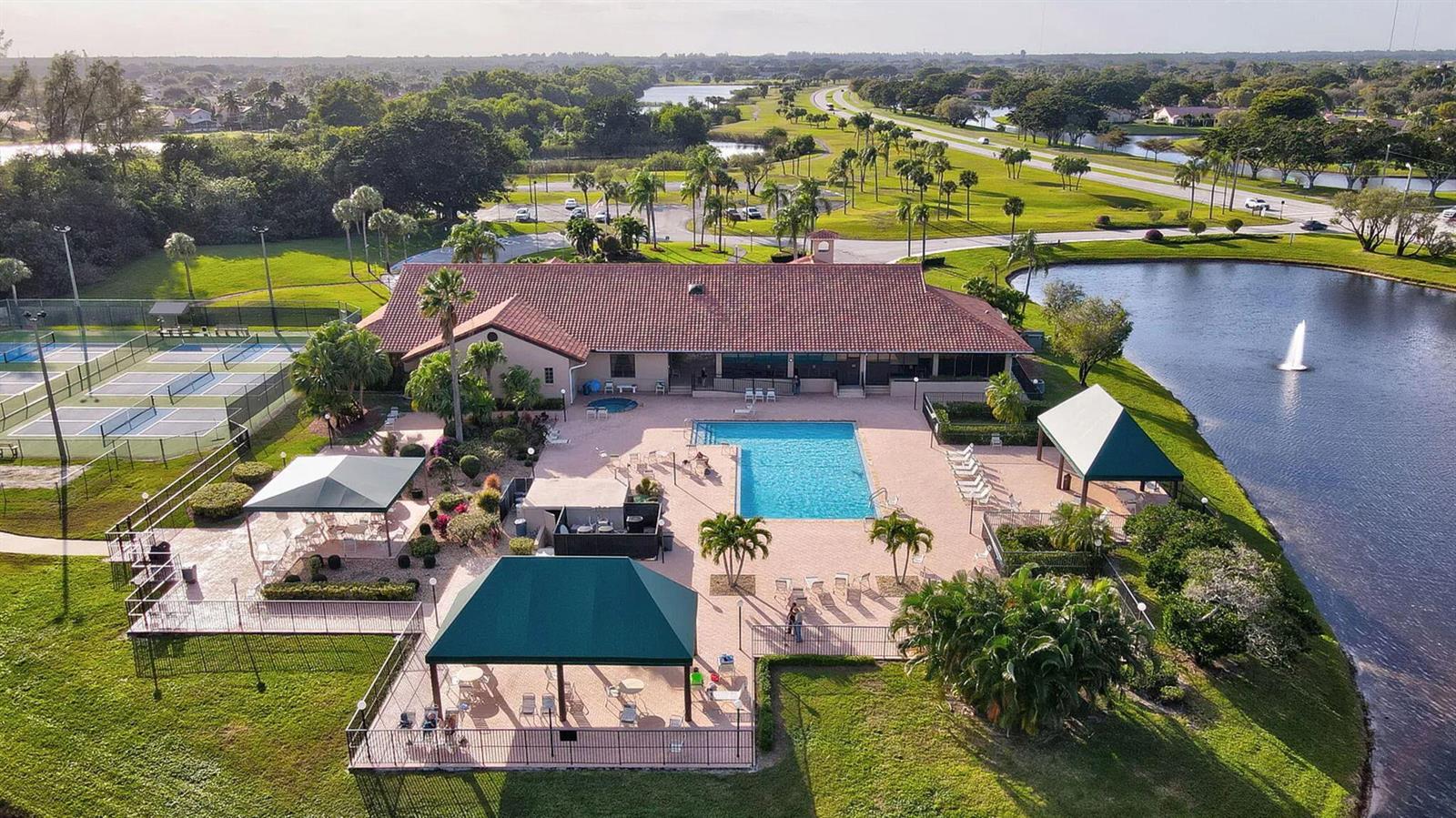 An aerial view shows a community clubhouse with a swimming pool, tennis courts, and pond — 5881 Parkwalk Drive, Boynton Beach FL 33472, BOYNTON BEACH, FL