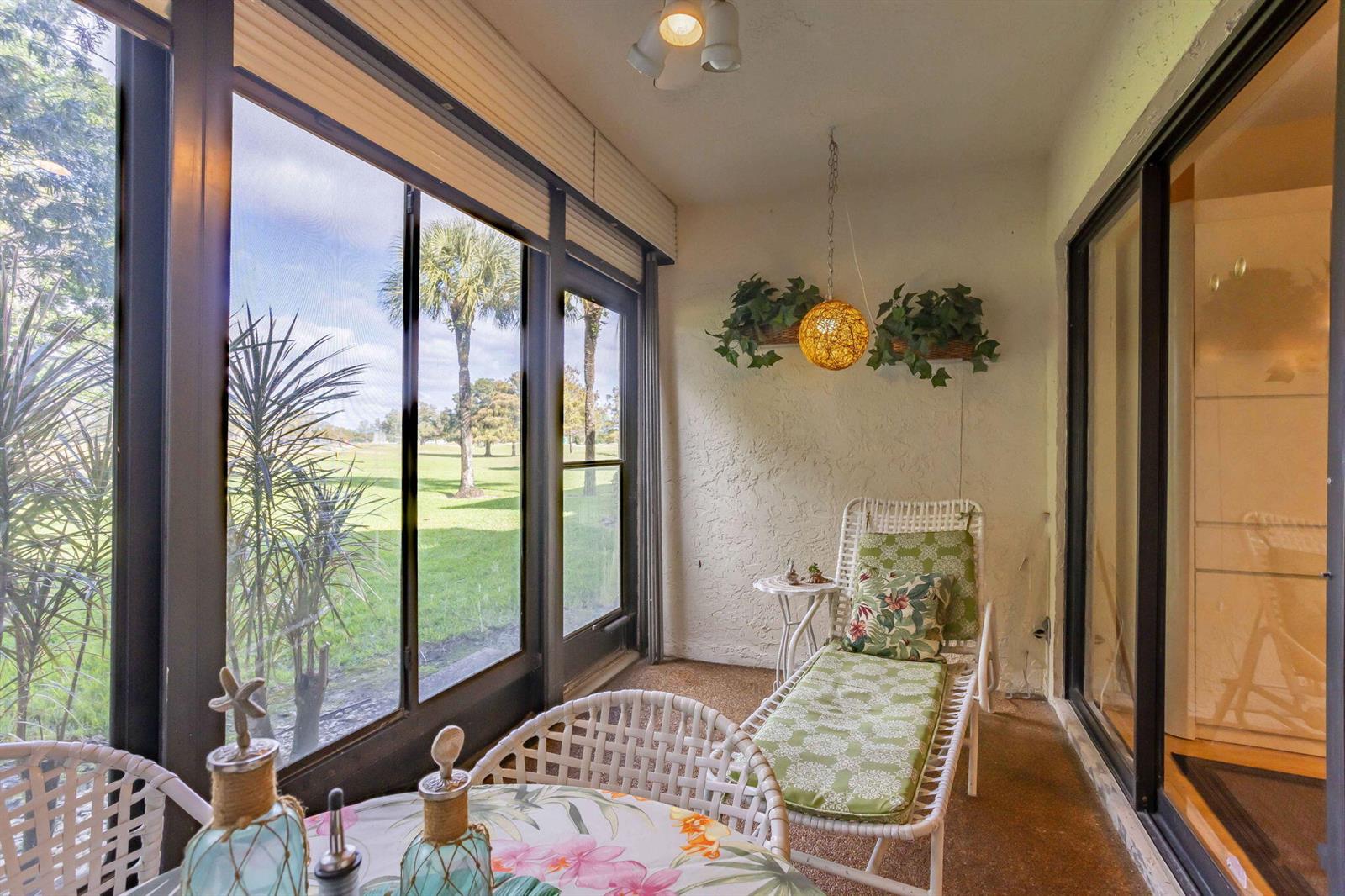 A screened-in porch with white wicker furniture, a hanging light, and views of a golf course — 5881 Parkwalk Drive, Boynton Beach FL 33472, BOYNTON BEACH, FL