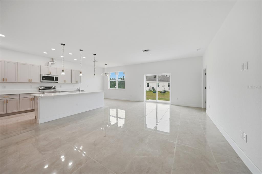 A bright, open-concept kitchen and living area features light-colored cabinetry, an island, and tile flooring — 14191 ONSLOW LANE, PORT CHARLOTTE, FL