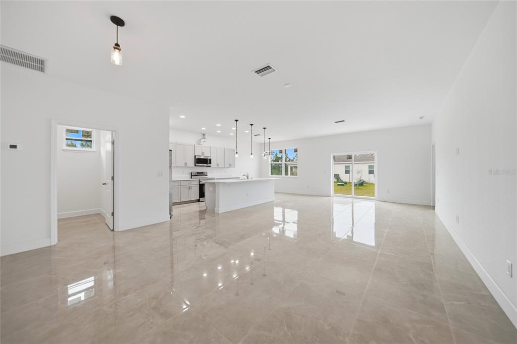A bright, open-concept kitchen and living area features white cabinetry, a kitchen island, and tile flooring — 14191 ONSLOW LANE, PORT CHARLOTTE, FL