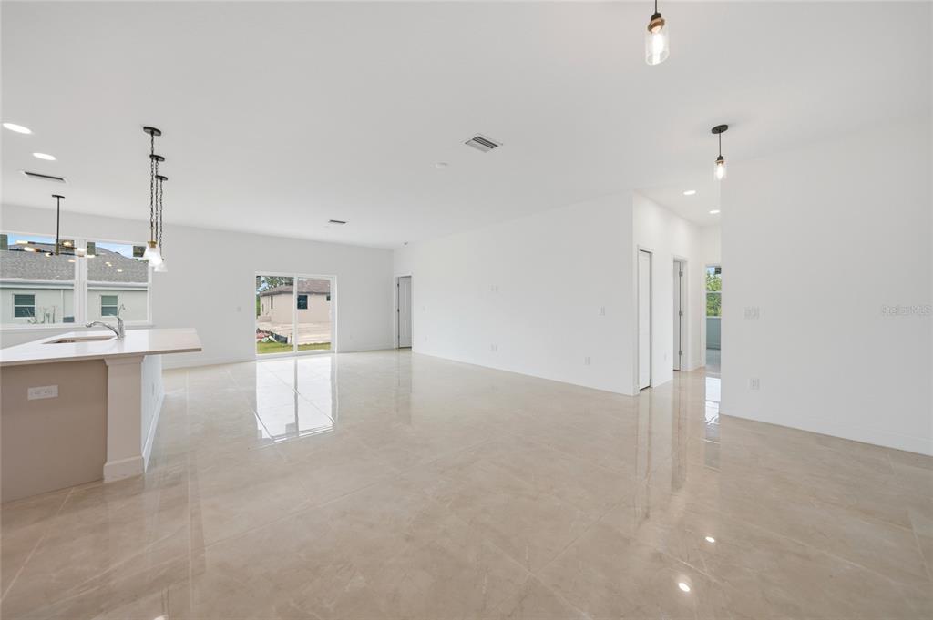 An open-concept living area features light tile flooring, white walls, and a sliding glass door — 14191 ONSLOW LANE, PORT CHARLOTTE, FL