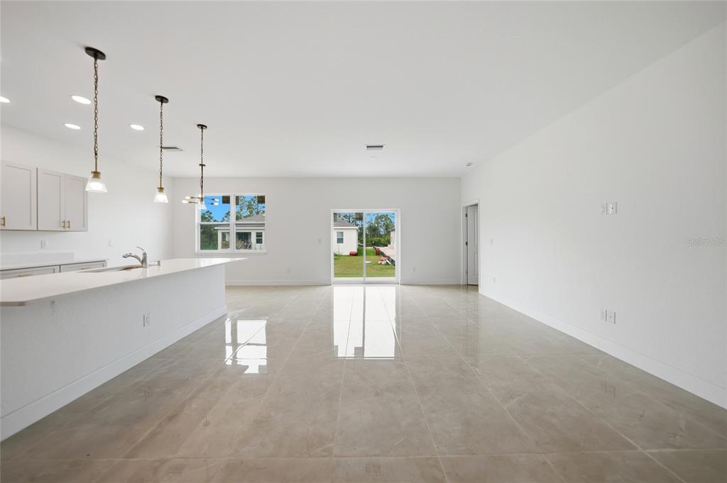 A bright, open-concept kitchen and living area with white cabinets, pendant lighting, and tile flooring — 14191 ONSLOW LANE, PORT CHARLOTTE, FL