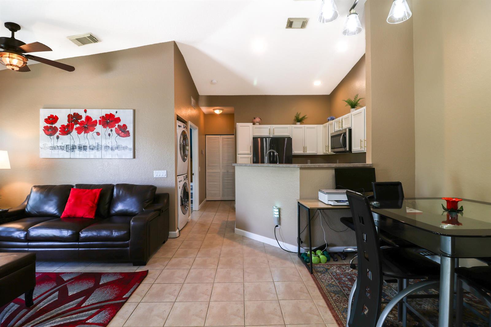 A living room with a leather sofa and a kitchen area with white cabinets — 3133 Laurel Ridge Circle, West Palm Beach FL 33404, WEST PALM BEACH, FL