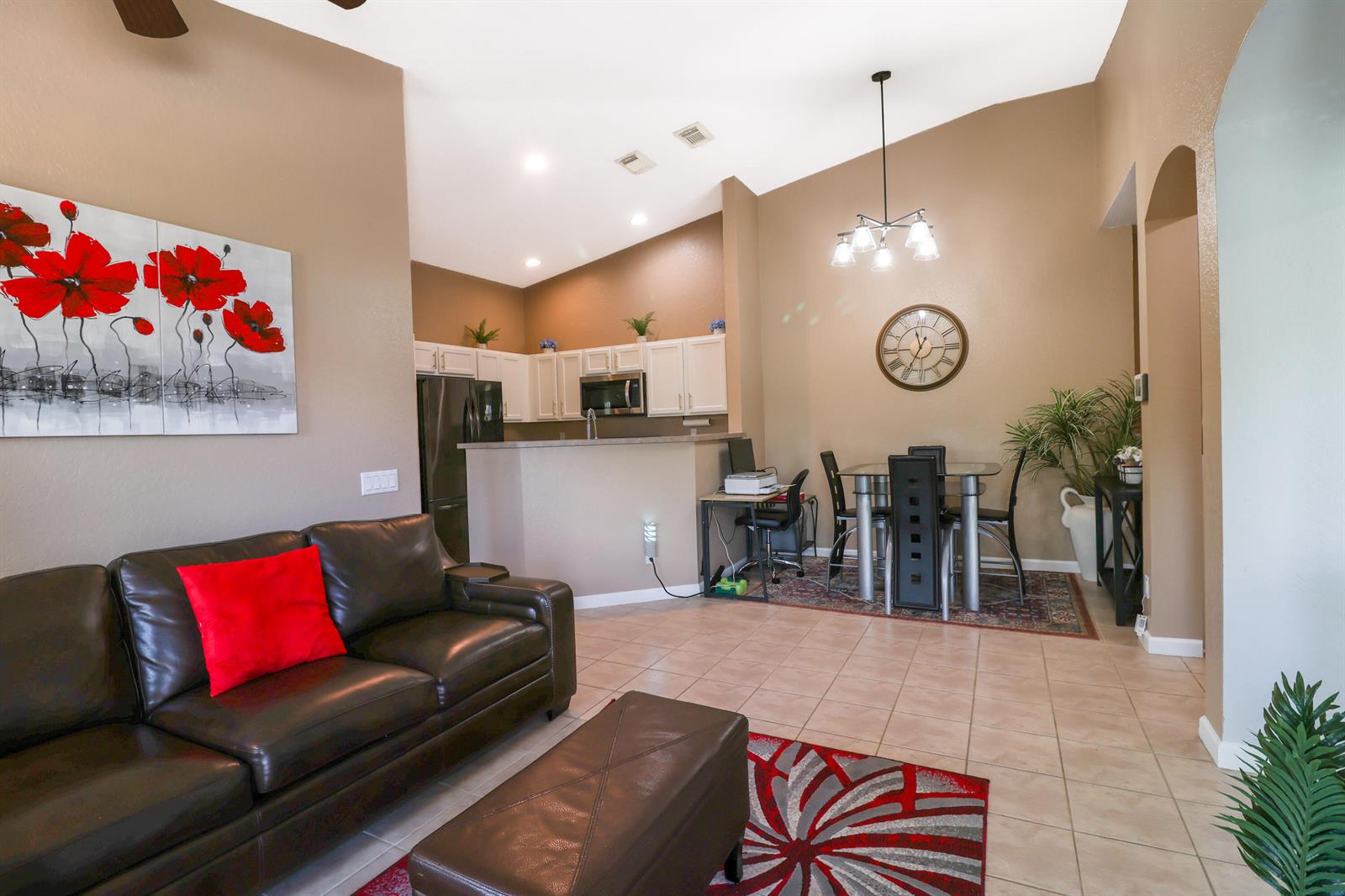 A living room with a brown leather sofa opens to a kitchen and dining area — 3133 Laurel Ridge Circle, West Palm Beach FL 33404, WEST PALM BEACH, FL