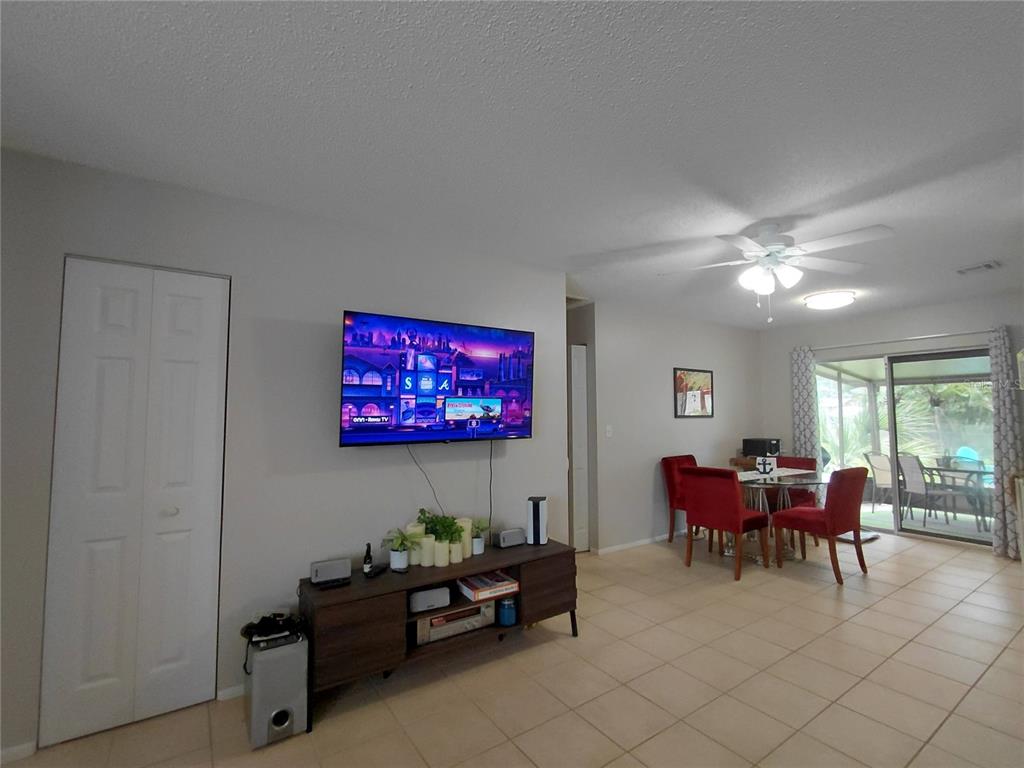 A living room with a wall-mounted television, media console, and an adjacent dining area — 351 TERRAPIN ROAD, VENICE, FL