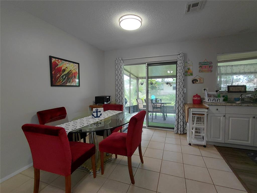A dining area with a glass table, red chairs, and a sliding door to a patio — 351 TERRAPIN ROAD, VENICE, FL