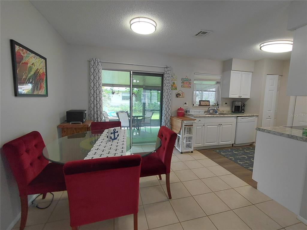A dining area with a glass table and red chairs sits adjacent to a kitchen — 351 TERRAPIN ROAD, VENICE, FL