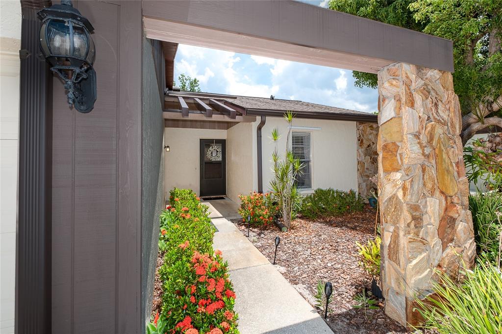 A concrete walkway leads to the front entrance of a house with stone accents — 206 ASPEN STREET, ENGLEWOOD, FL
