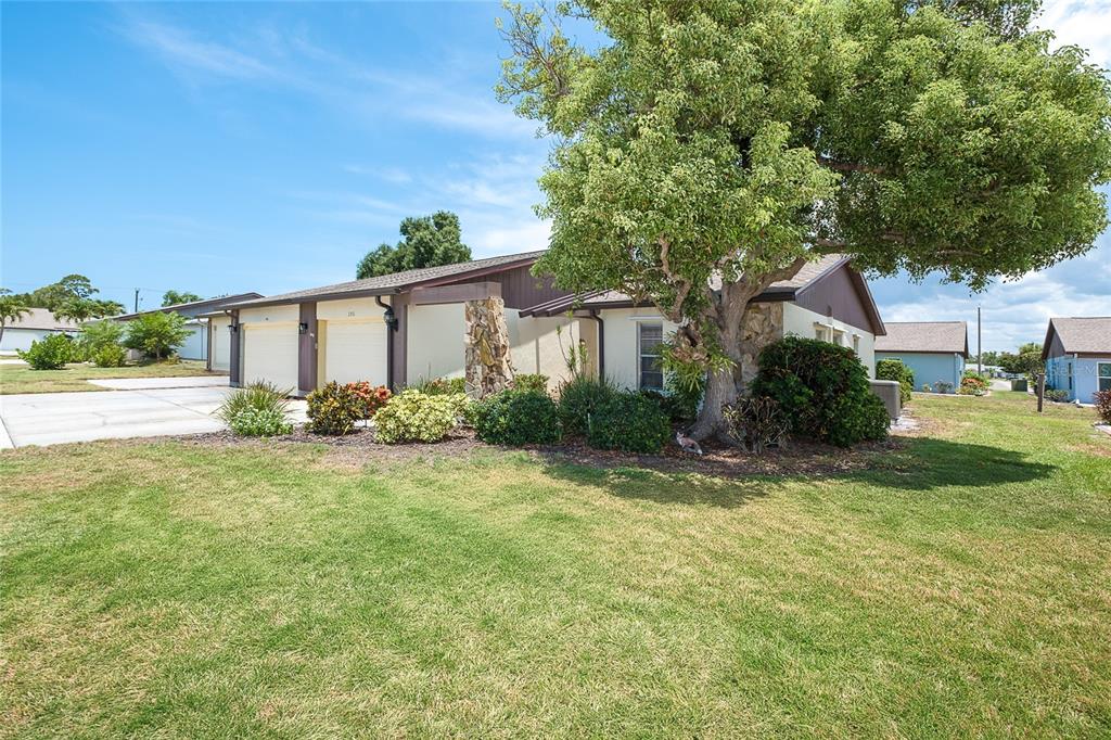 A single-story house with a two-car garage, stone accents, and a large tree in front — 206 ASPEN STREET, ENGLEWOOD, FL