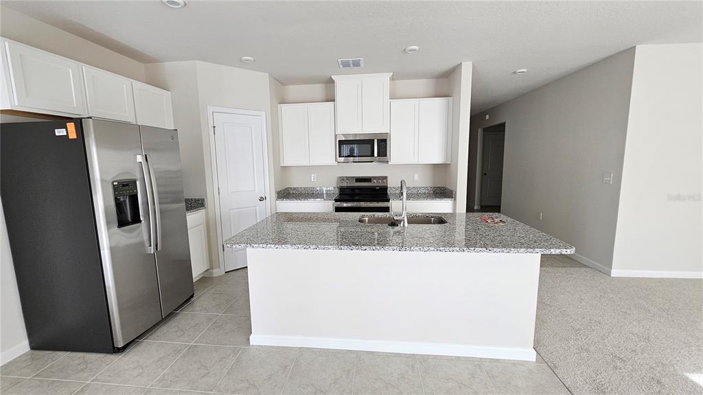 A kitchen features white cabinets, granite countertops, a stainless steel refrigerator, and a center island — 347 BILTMORE BOULEVARD, DUNDEE, FL