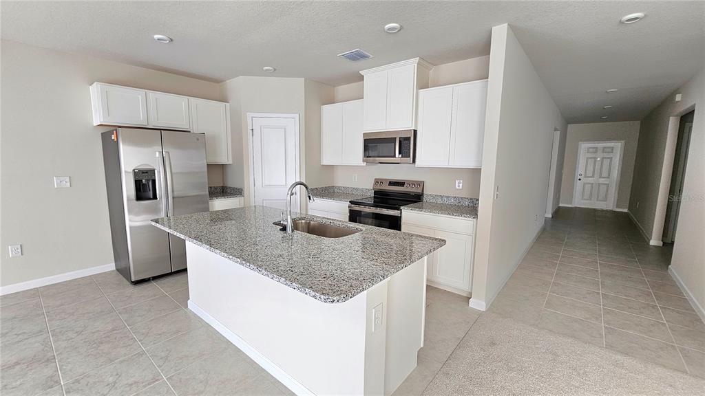 A kitchen features white cabinets, granite countertops, a center island, and stainless steel appliances — 347 BILTMORE BOULEVARD, DUNDEE, FL