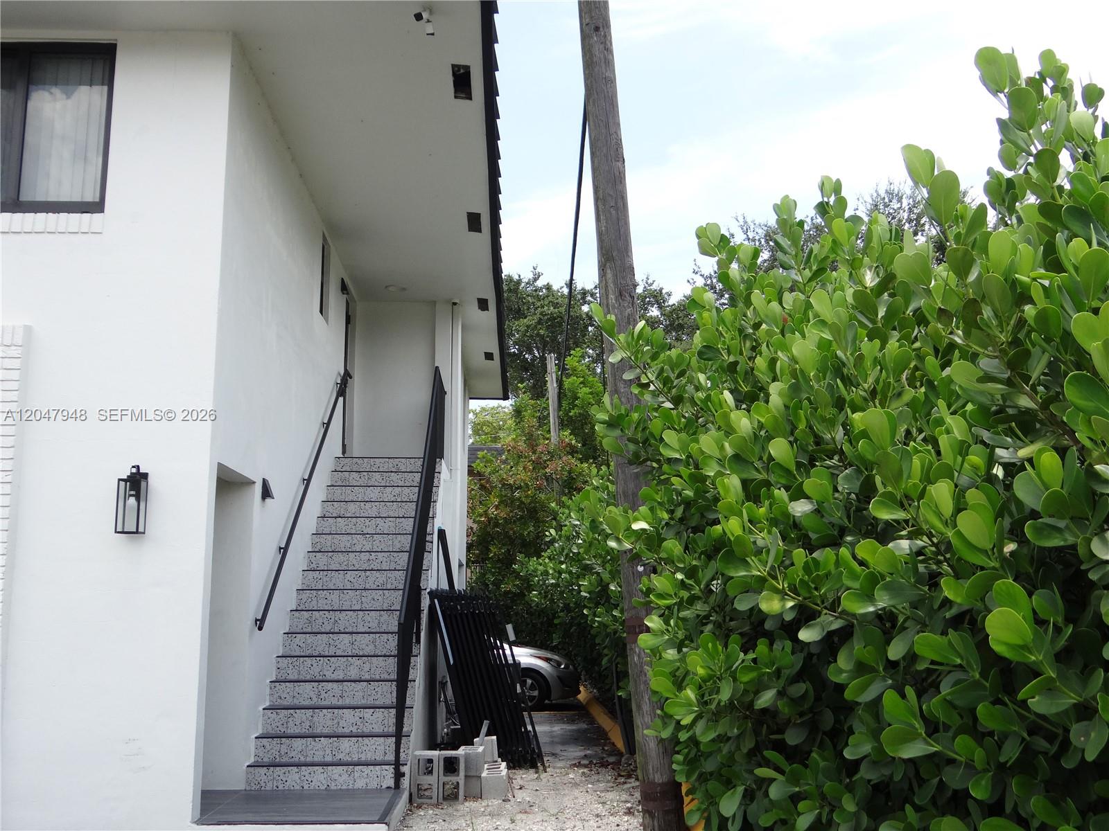 An exterior view shows a white building with a staircase leading to an upper level — 5980 SW 40th Ave # D, Dania Beach FL 33312, DANIA BEACH, FL
