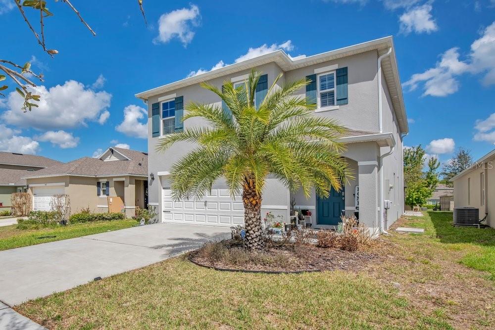 A two-story suburban house with a gray exterior, a palm tree, and a concrete driveway — 410 LADY BELLA PLACE, DELAND, FL