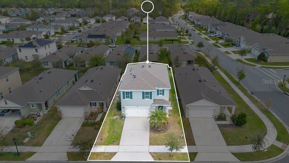 An aerial view shows a two-story suburban house with a white garage and blue shutters — 410 LADY BELLA PLACE, DELAND, FL