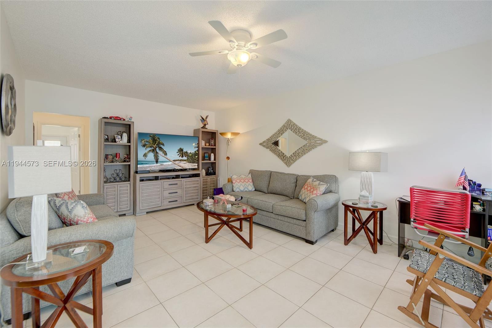 A living room features gray sofas, a television console, tile flooring, and a ceiling fan — 800 SW 11th Ave # 9A, Hallandale Beach FL 33009, HALLANDALE BEACH, FL