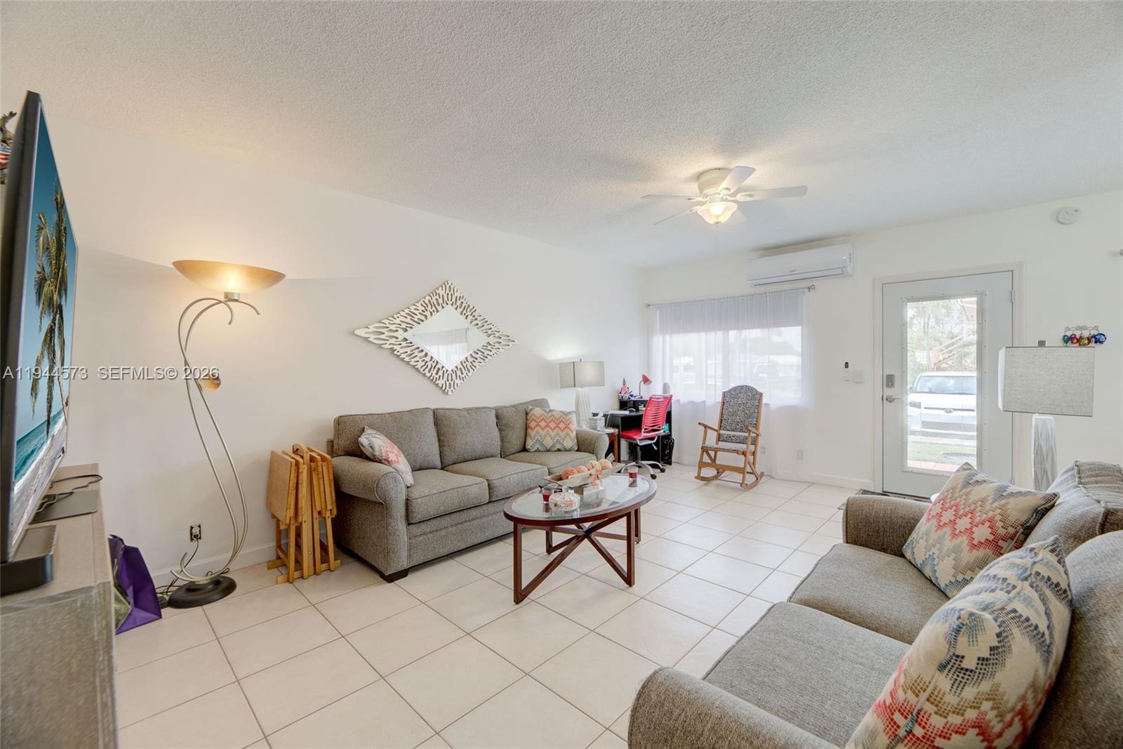 A living room features two gray sofas, a coffee table, a floor lamp, and tile flooring — 800 SW 11th Ave # 9A, Hallandale Beach FL 33009, HALLANDALE BEACH, FL