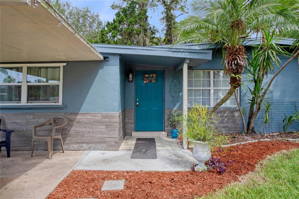 The exterior of a blue house features a teal front door and wood-look siding — 7329 ROYAL PALM DRIVE, NEW PORT RICHEY, FL