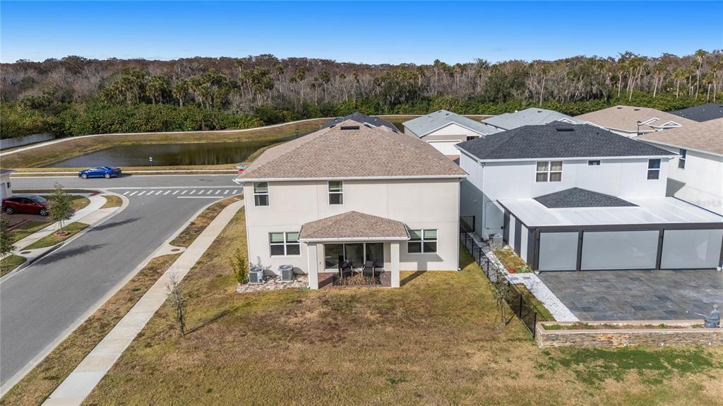 An aerial view shows the rear exterior of a two-story house with a covered patio — 3437 MCLAIN PRESERVE POINT, SANFORD, FL