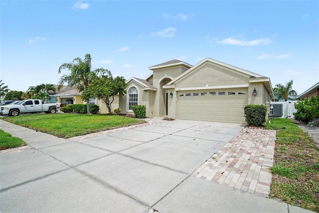 A single-story house with a beige stucco exterior, a two-car garage, and a paved driveway — 2519 BIG PINE DRIVE, HOLIDAY, FL