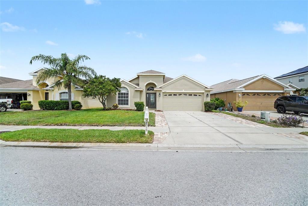 A single-story suburban house with a beige stucco exterior and a two-car garage — 2519 BIG PINE DRIVE, HOLIDAY, FL