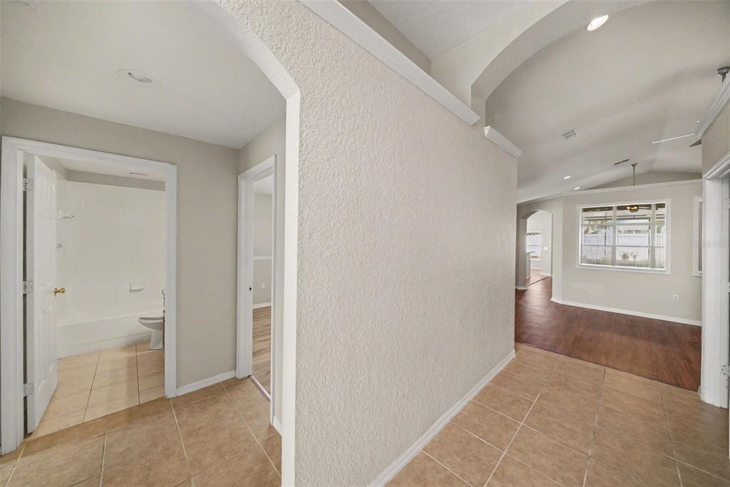 A hallway with tile flooring leads to a bathroom on the left and a living area — 2519 BIG PINE DRIVE, HOLIDAY, FL
