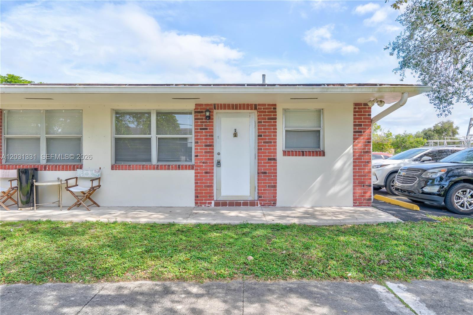 A single-story building exterior features a white door, brick accents, and a concrete walkway — 856 SW 10th St # 1, Hallandale Beach FL 33009, HALLANDALE BEACH, FL