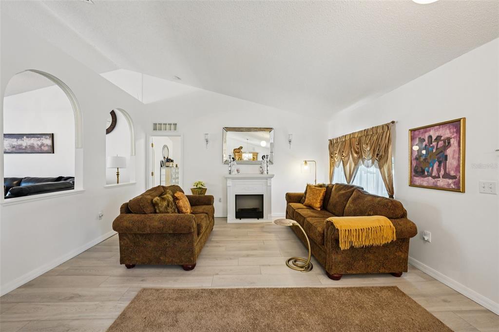 A living room features two brown sofas, a fireplace, and light wood-look flooring — 10423 BRADFORD STREET, SPRING HILL, FL