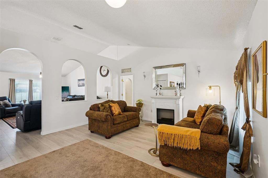 A living room features light wood-look flooring, a white fireplace, and two brown sofas — 10423 BRADFORD STREET, SPRING HILL, FL