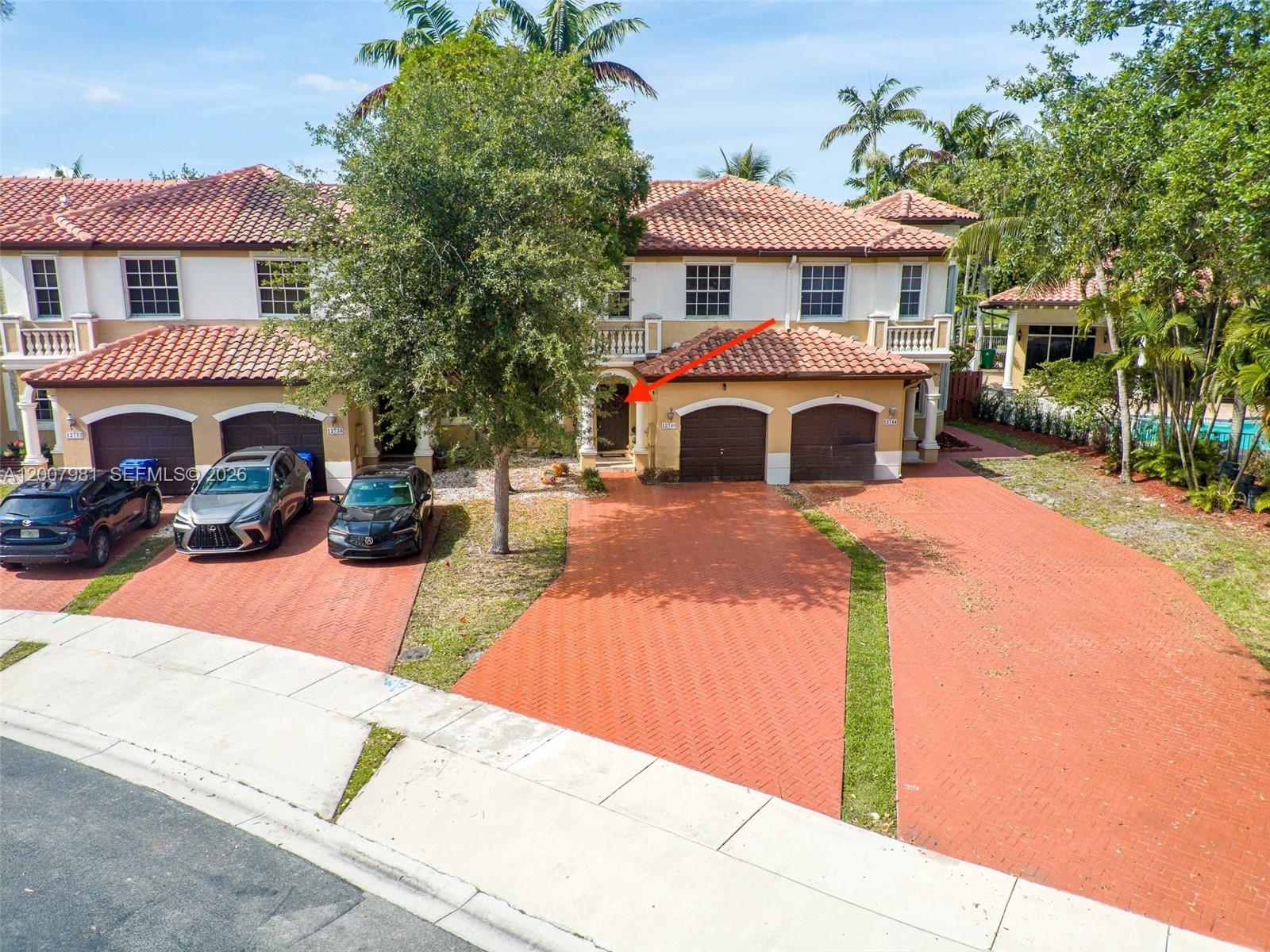An exterior view of a two-story townhouse with a red tile roof and brick driveway — 12740 SW 50th St, Miramar FL 33027, MIRAMAR, FL
