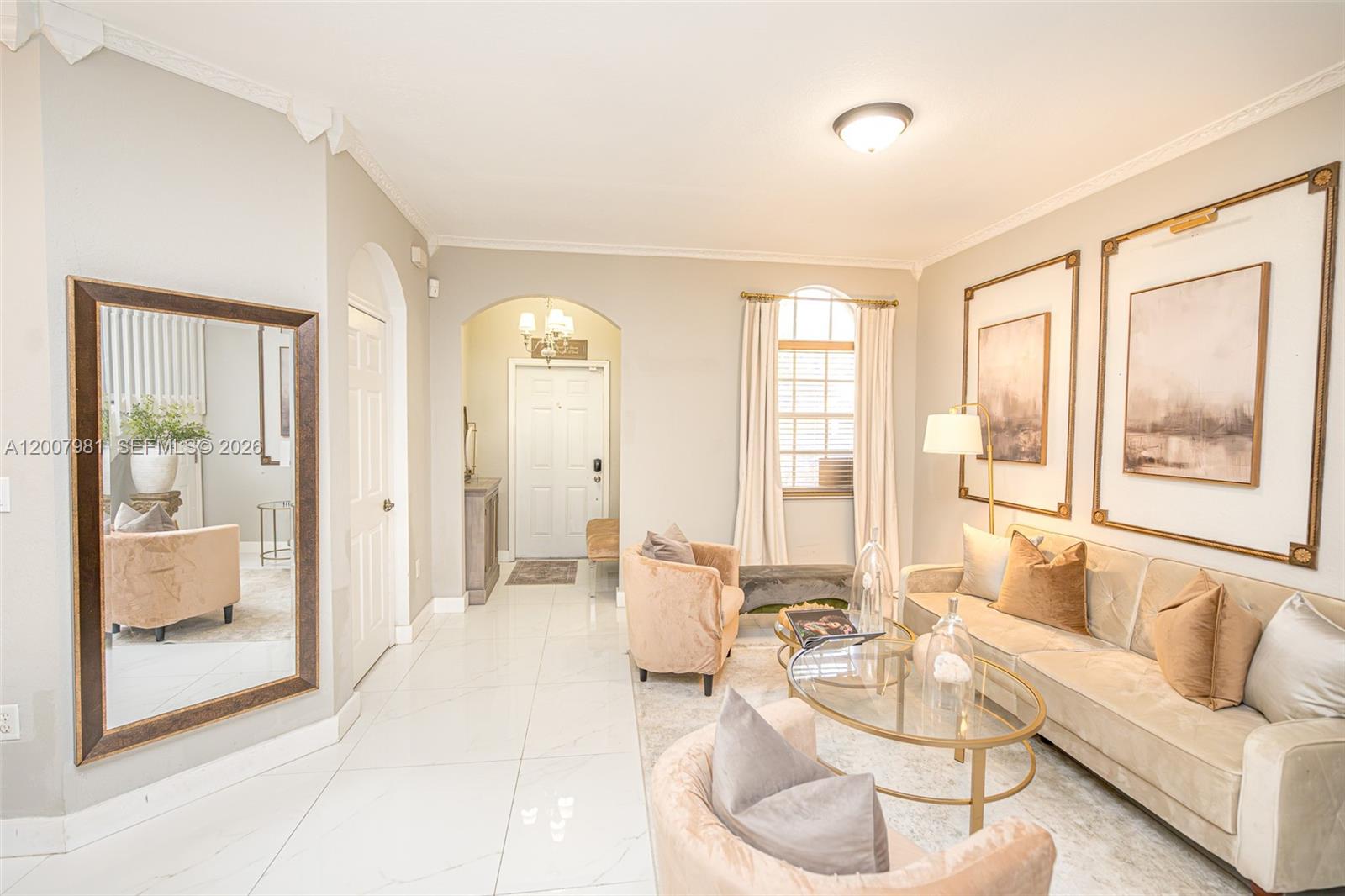 A bright living room features light tile floors, a velvet sofa, and arched entryways — 12740 SW 50th St, Miramar FL 33027, MIRAMAR, FL