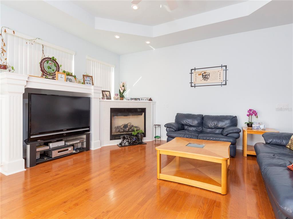 A living room features hardwood floors, a fireplace, a television, and dark leather furniture — 1486 SW 87TH STREET, GAINESVILLE, FL
