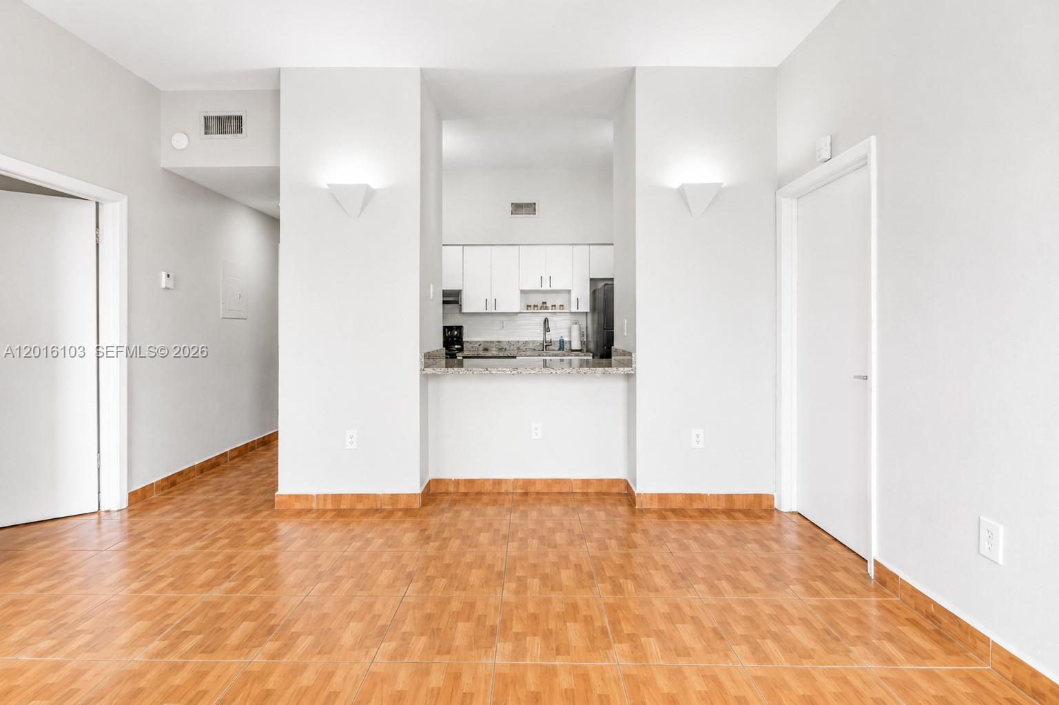 A room with orange tile flooring features a kitchen pass-through window and white walls — 7400 W 20th Ave # 312, Hialeah FL 33016, HIALEAH, FL