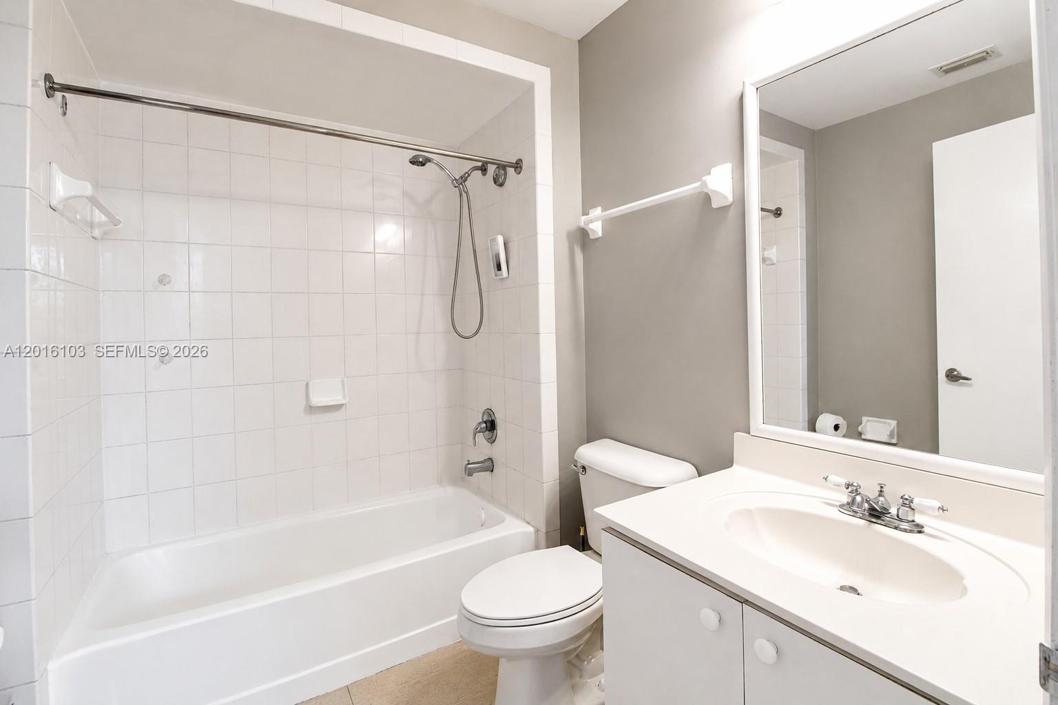 A bathroom features a white vanity, a toilet, and a tiled shower-tub combination — 7400 W 20th Ave # 312, Hialeah FL 33016, HIALEAH, FL
