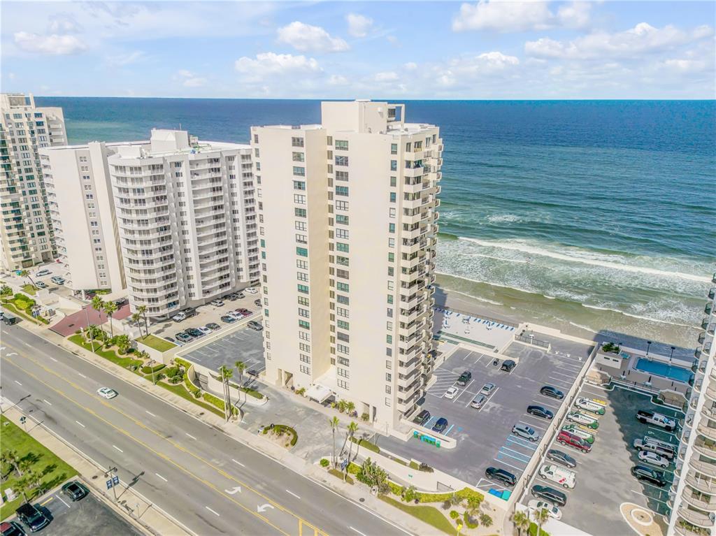 An aerial view shows two high-rise beachfront condominiums with parking lots and a coastal road — 2987 S ATLANTIC AVENUE UNIT 1104, DAYTONA BEACH, FL