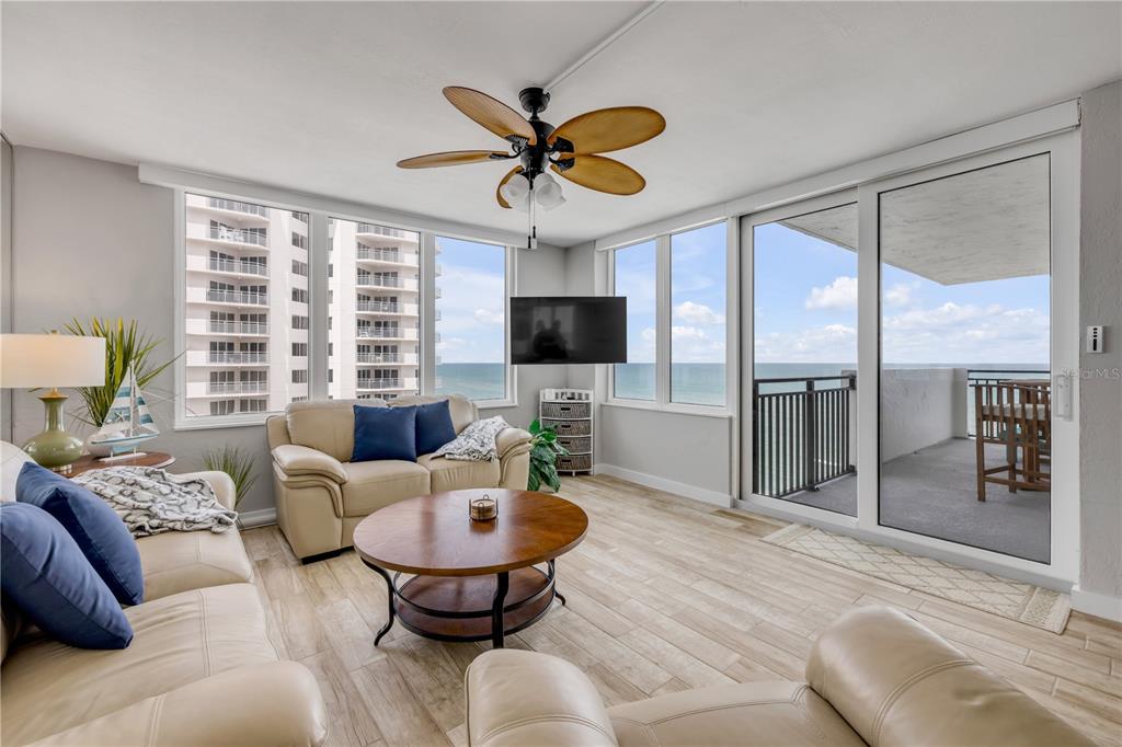 A living room with beige sofas, a round wooden coffee table, and a balcony overlooking the ocean — 2987 S ATLANTIC AVENUE UNIT 1104, DAYTONA BEACH, FL