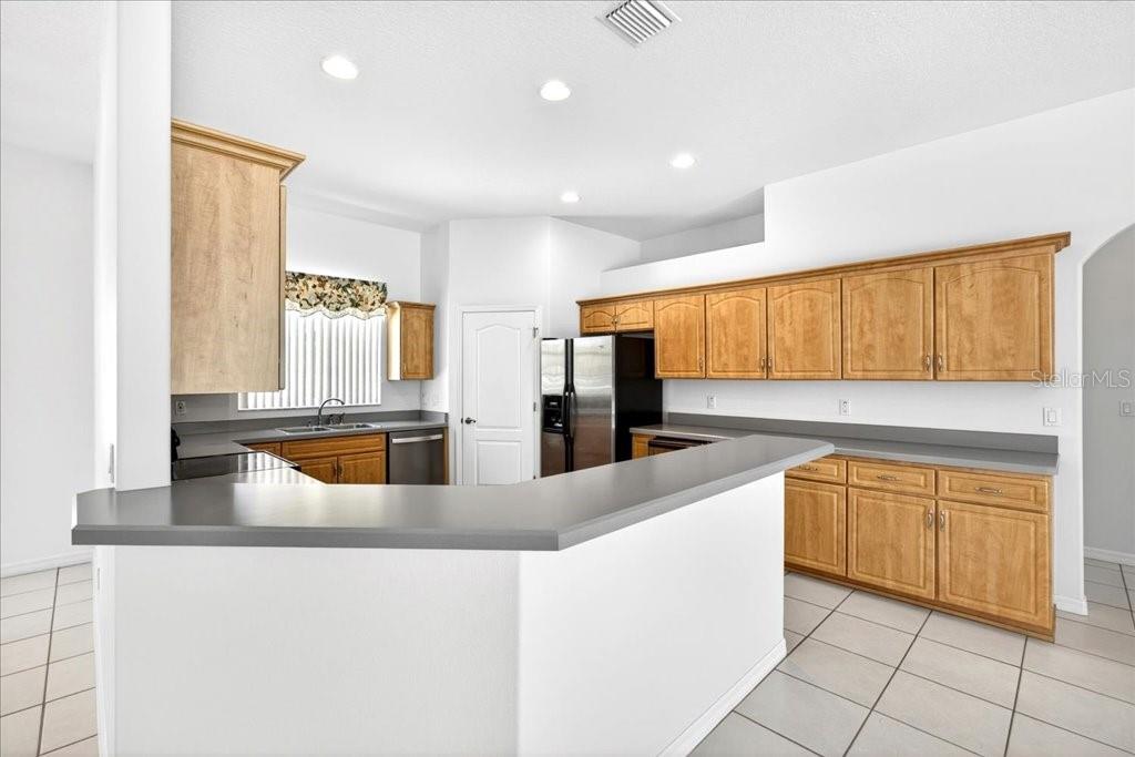 A kitchen with light wood cabinets, gray countertops, and tile flooring — 25 WESTMINSTER DRIVE, PALM COAST, FL