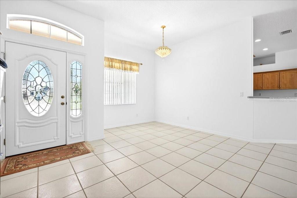 A dining area features white walls, tile flooring, a chandelier, and a front entry door — 25 WESTMINSTER DRIVE, PALM COAST, FL