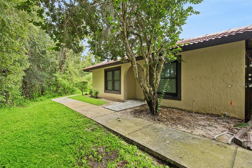A concrete walkway leads to the front entrance of a tan house with a tiled roof — 530 HUNTER CIRCLE, KISSIMMEE, FL